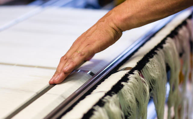 Processus de fabrication : Préparation des fils de chaîne au tissage : mise en place sur le métier.